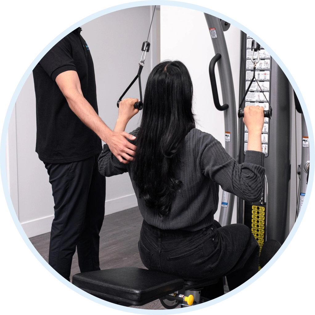 A Smart Motion Physiotherapy clinician assists a patient with a resistance pulley exercise for shoulder strengthening.